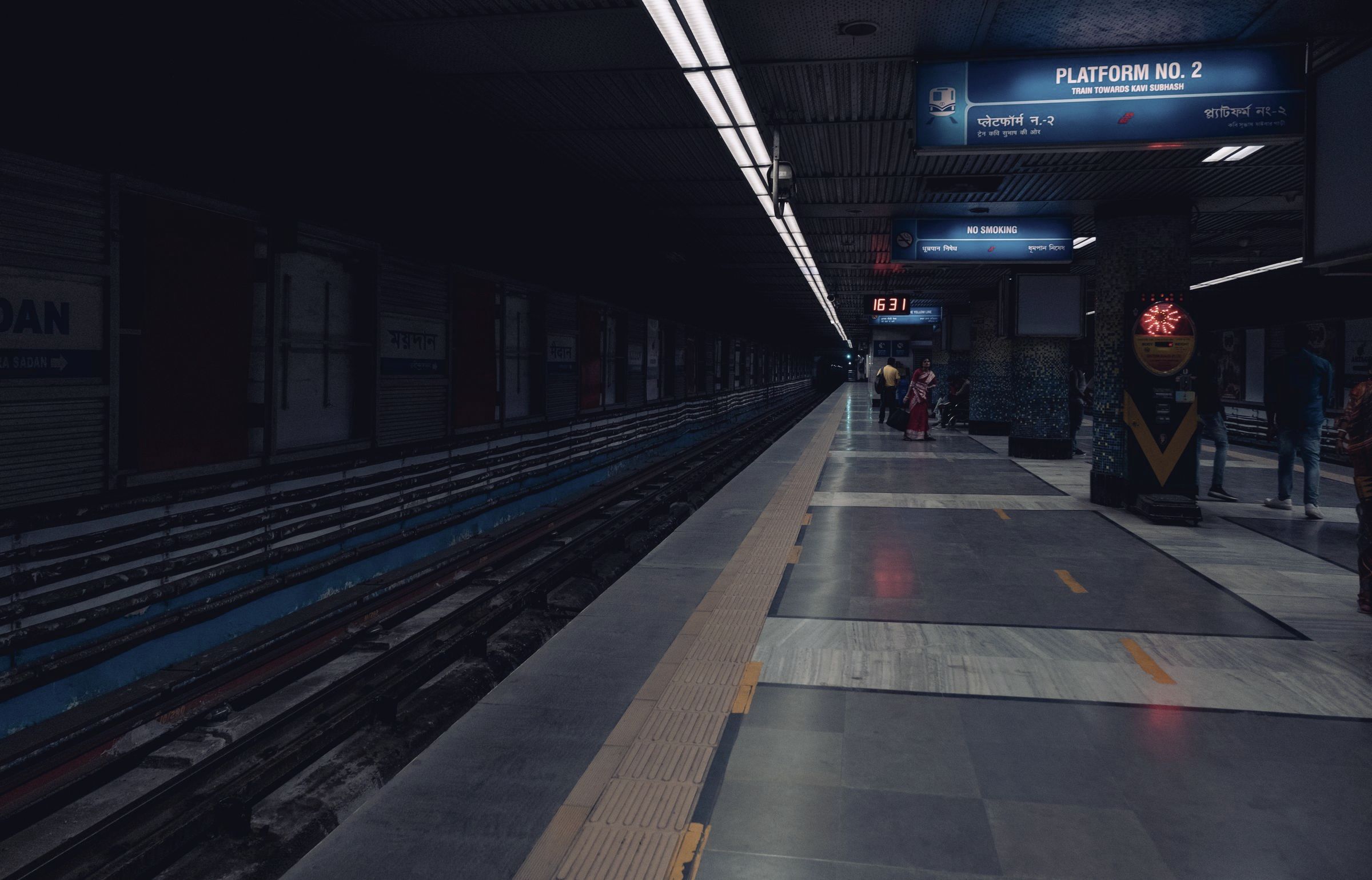 An empty subway platform under strip lighting.