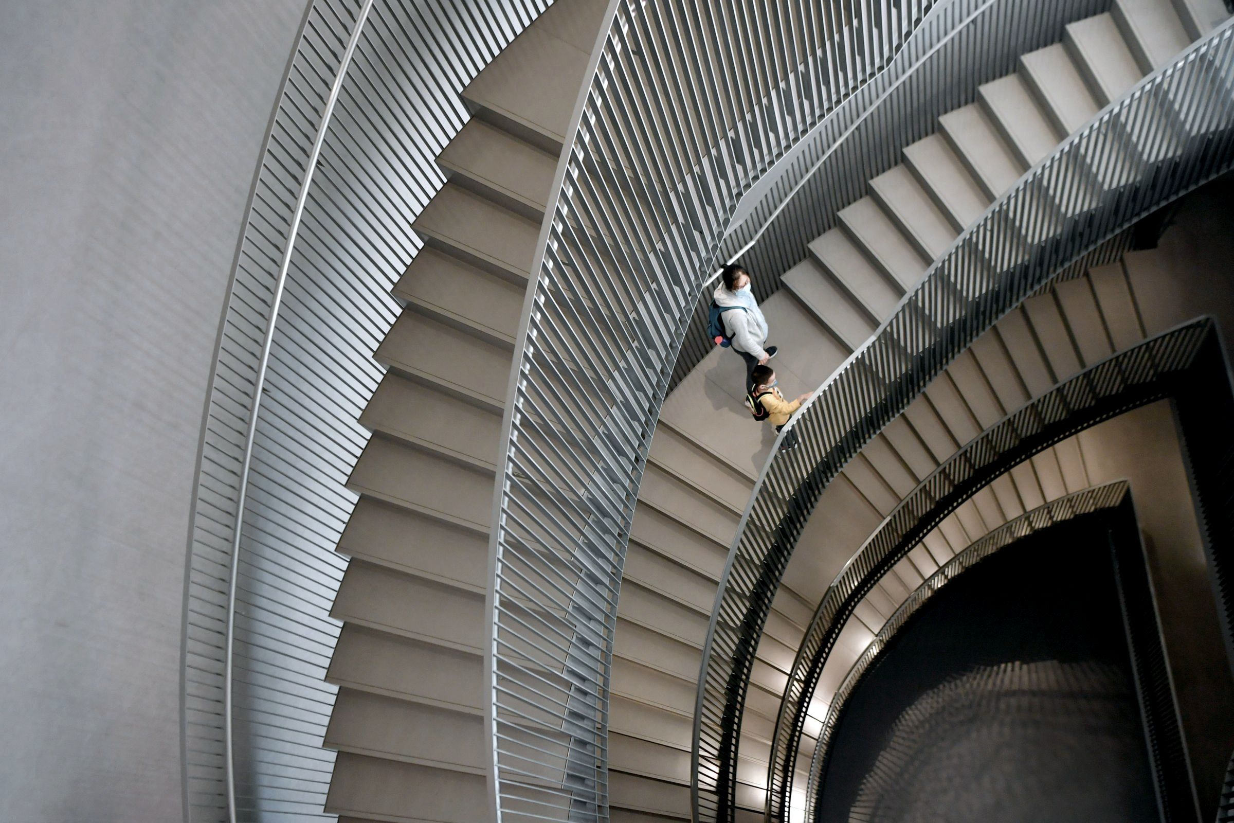 A curved white staircase from above with one person on it.