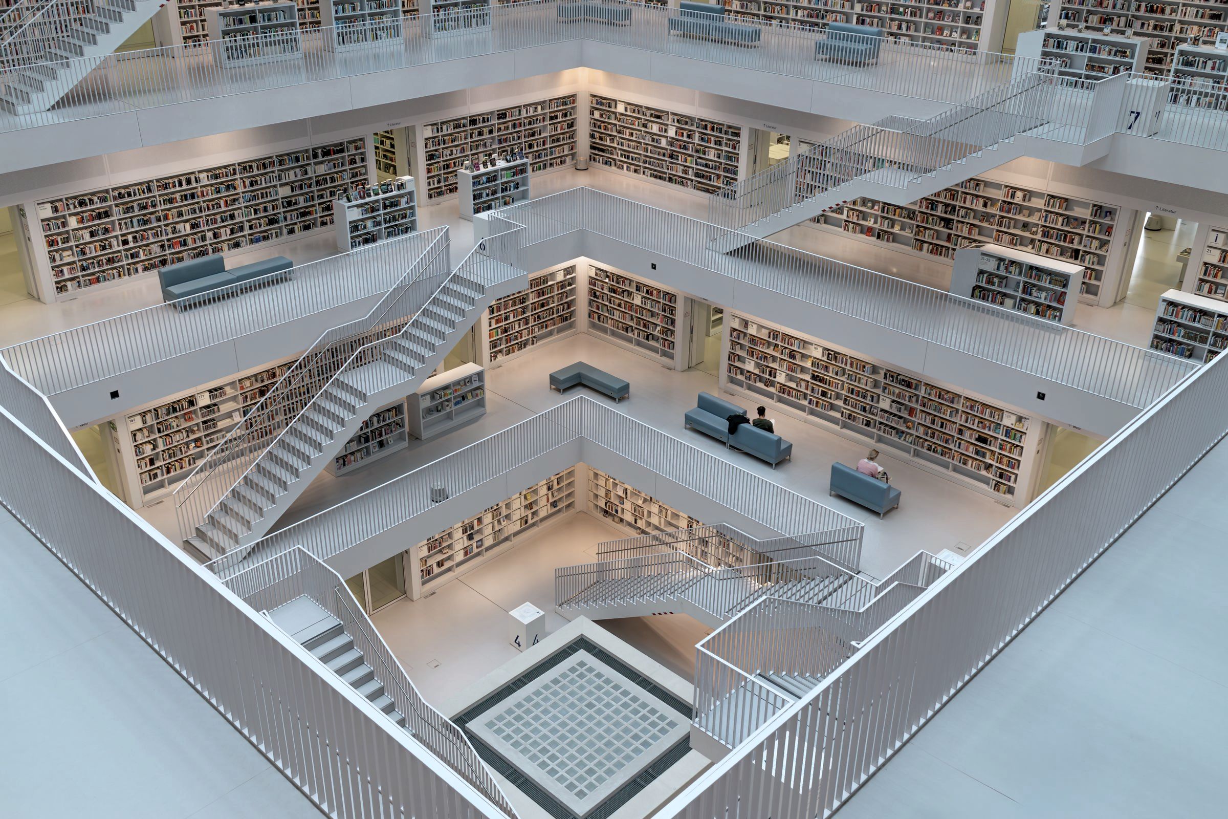 A white library of five galleries around an open well, stairs crossing between the floors.