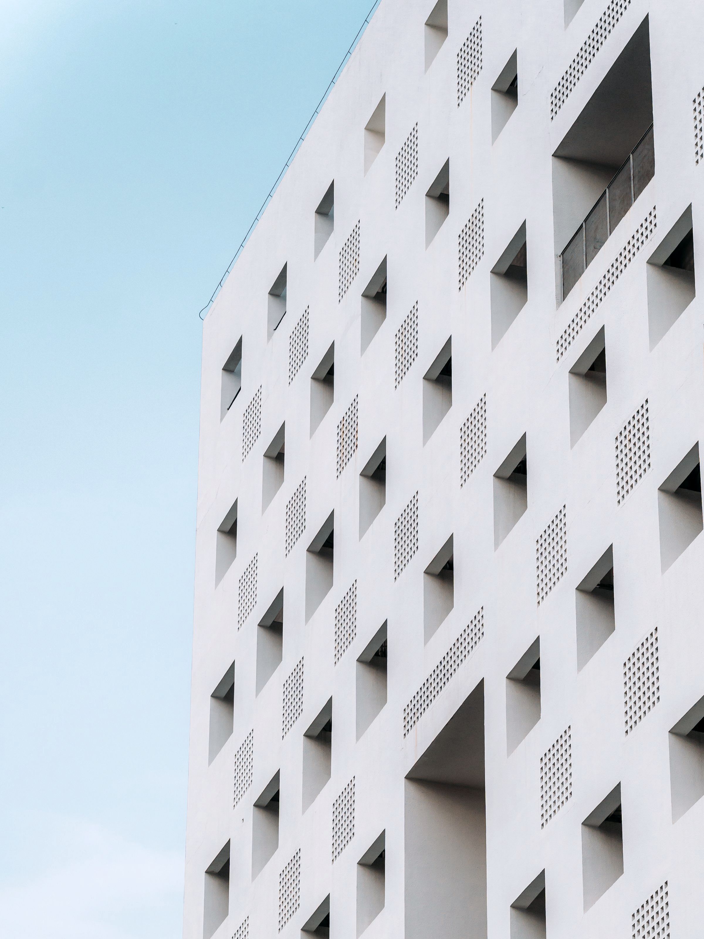 The corner of a white facade, its windows set deep behind angled hoods.