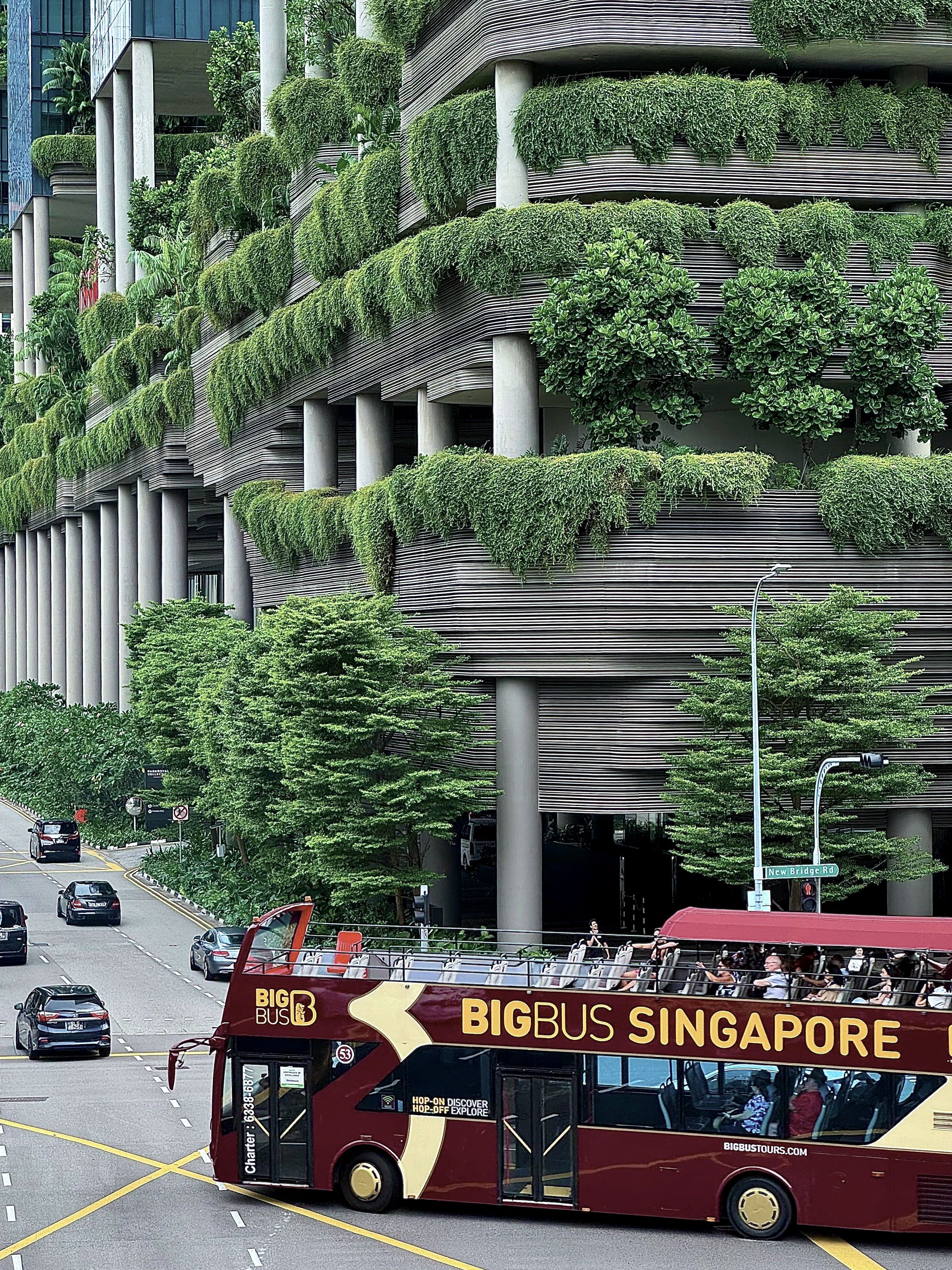 Planting spilling over the floors of a building in Singapore, traffic on the street below.