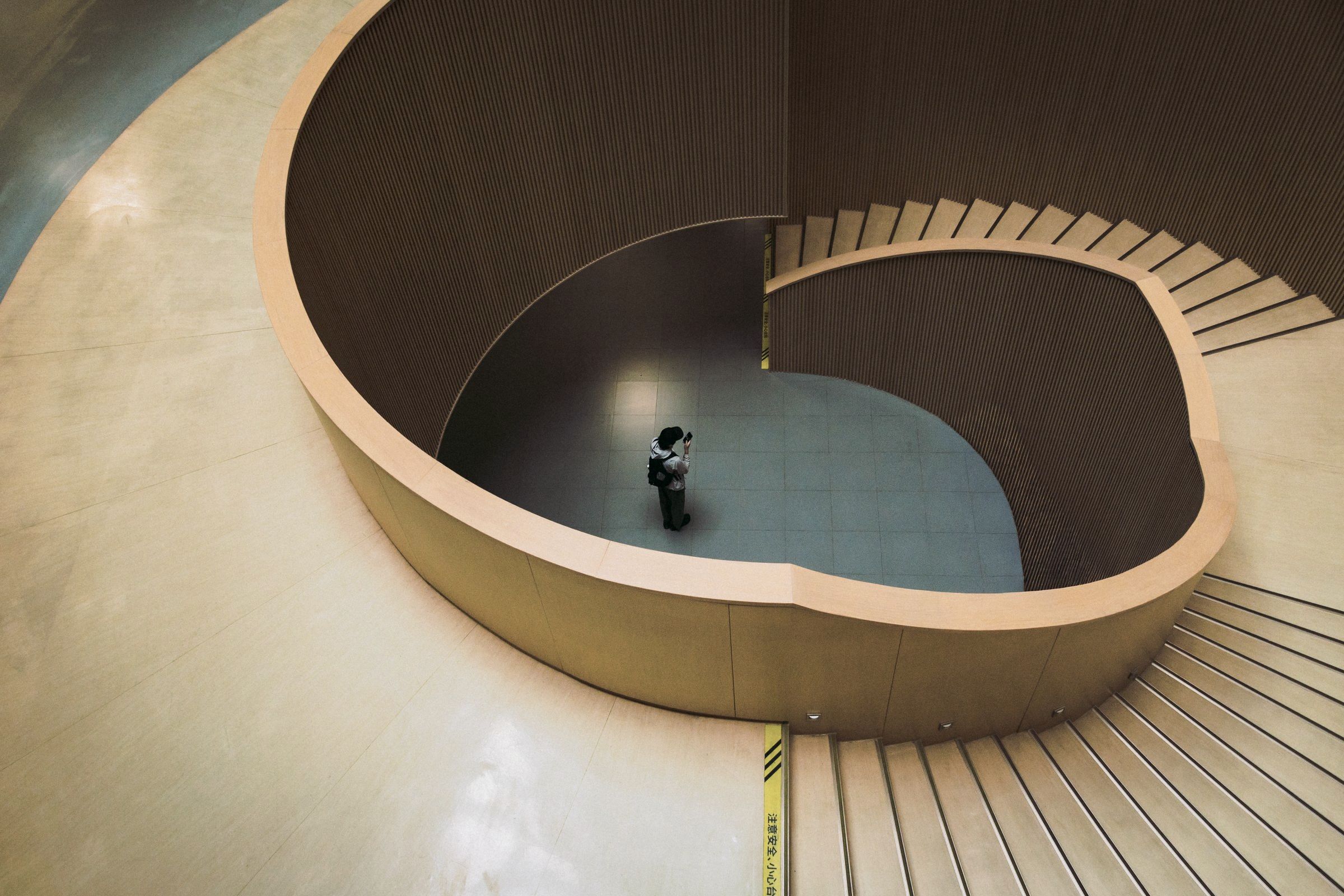 A curved timber staircase from above, one person on it.