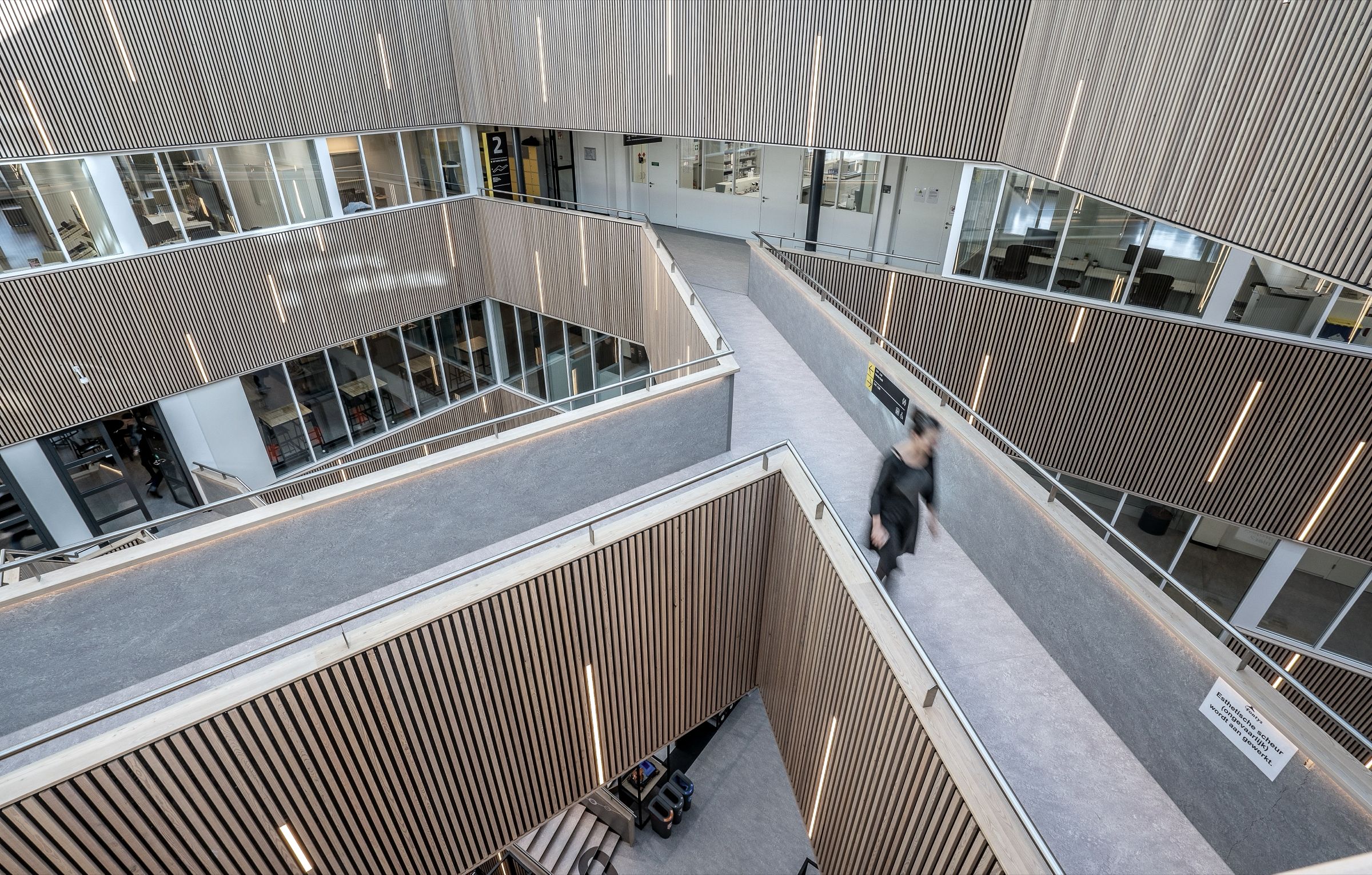 View down into a timber-lined atrium, with a few people on the lower floors.